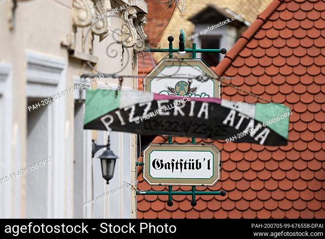 29 June 2020, Saxony, Leisnig: Signs of a pizzeria and a restaurant hang in the historic old town. Like many other small towns with medieval roots