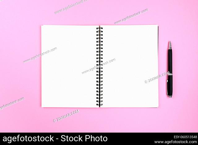 blank pages of open spiral notepad and pencil on pink background