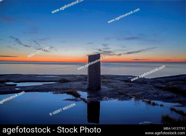 blue lighted sea landscape with a stone pillar reflected