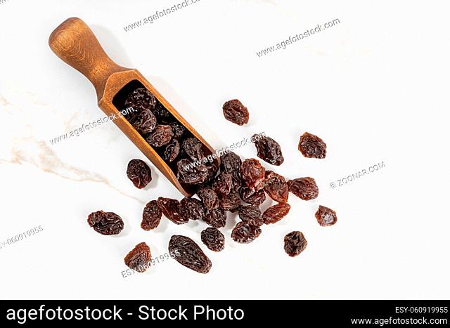 Raisins and scoop isolated on White marble Background. Dried grape. Copy space
