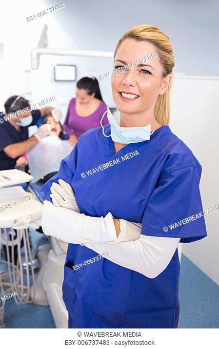 Nurse with folded arms with patient and dentist behind her