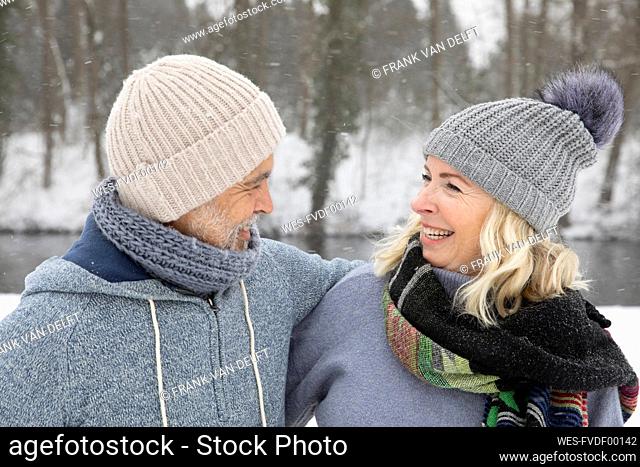 Happy senior couple in warm clothing looking at each other during winter