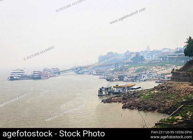 PRODUCTION - 02 November 2023, Brazil, Parintins: Boats and ships are covered in smoke during a forest fire at the harbor