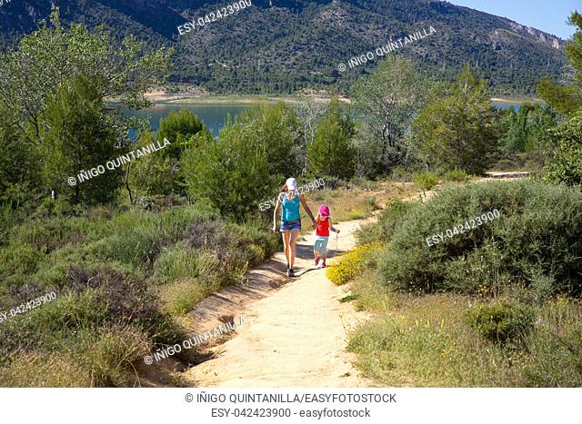 path with little girl four years old and woman hiking on summer in countryside next to the reservoir of Buendia (in Guadalajara, Spain, Europe)