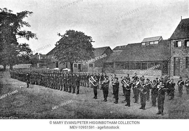 Boys on rifle drill parade at the Kingswood Reformatory, near Bristol. The School's Band stands alongside