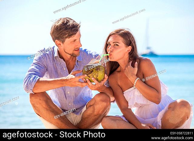 Young couple enjoying their time drinking a coconut cocktail on beach