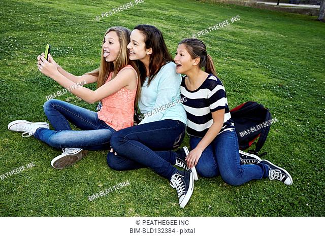 Teenage girls taking pictures in grass