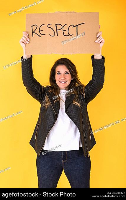 Homosexual woman smiling holding a sign asking for respect on yellow background
