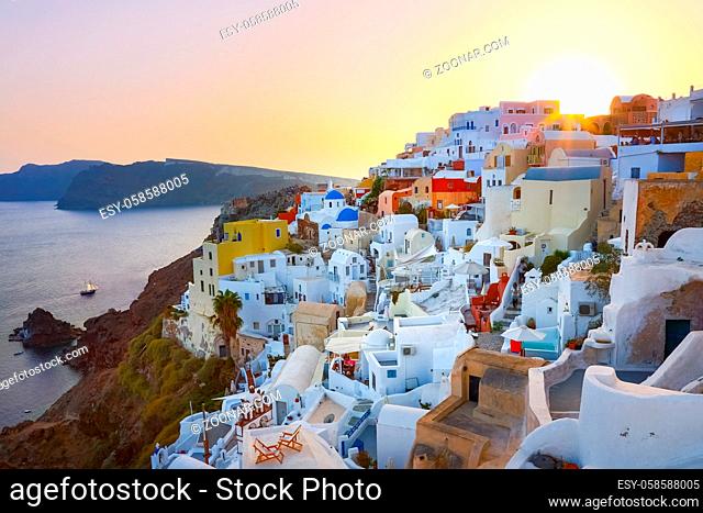 World famous traditional whitewashed chuches and houses of Oia village on Santorini island, Greece. Sunset