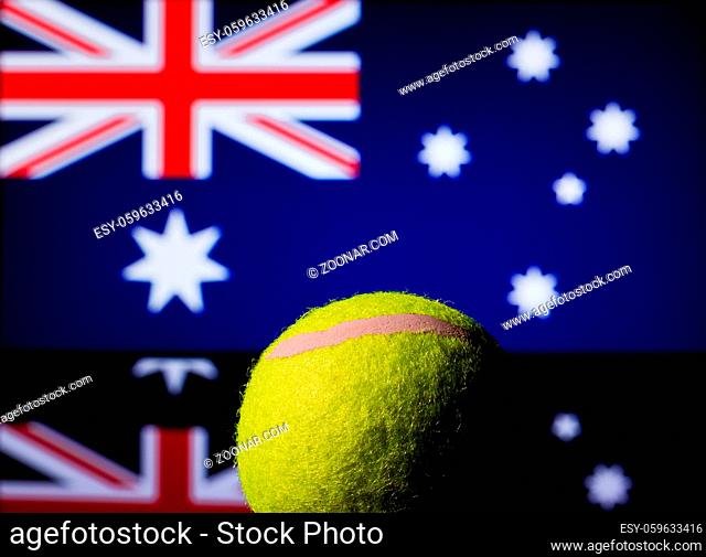 Yellow Tennis Ball on black mirror with Australian Flag in the background out of focus