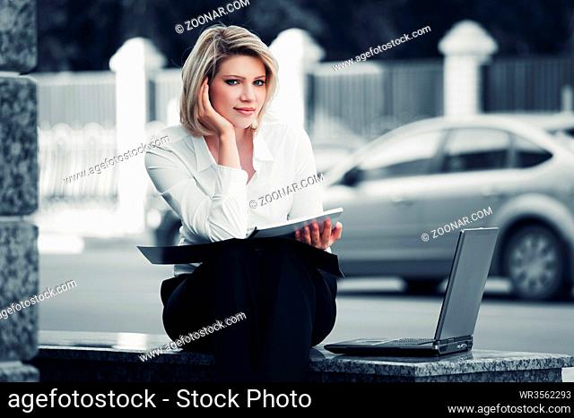Young business woman with laptop at the office wall