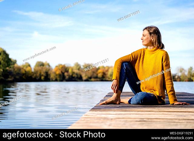 Woman sitting on jetty under sky