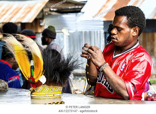 Man and headdress of bird of paradise or cassowary feathers for sale at the market, Wamena, Papua, Indonesia