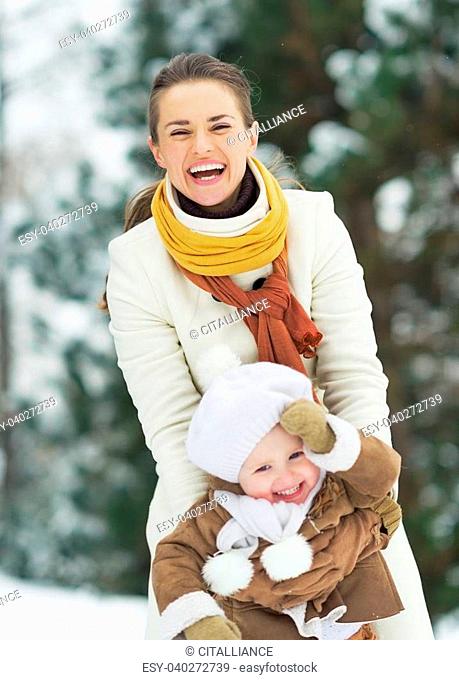 Happy mother playing with baby in winter park