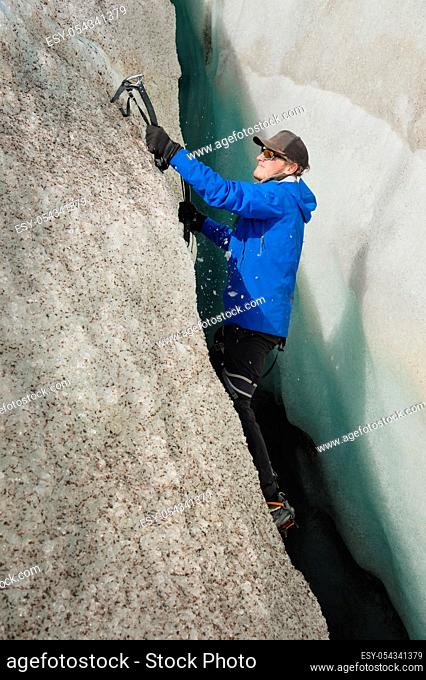 A free climber without insurance with two ice axes rises from a crack in the glacier. Free climbing without ropes