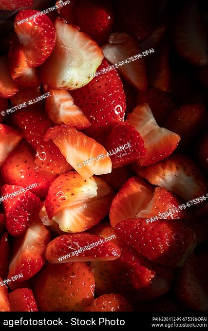 ILLUSTRATION - 12 April 2020, Bavaria, Nuremberg: Fresh edible berries cut into pieces lie in a container. These fruits come from the supermarket