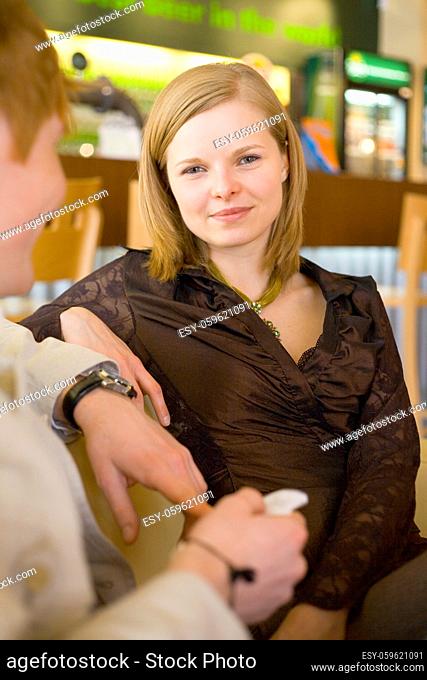 Woman's sitting at Cafe. There's a man next to her. Short depth of focus on woman's face
