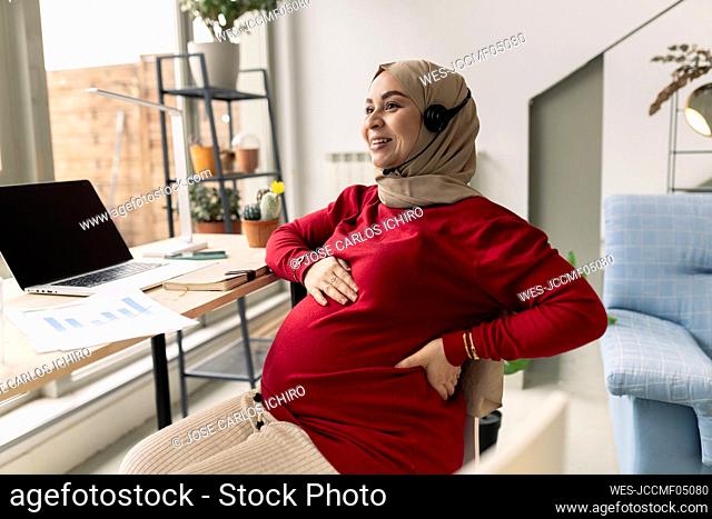 Smiling pregnant businesswoman freelancing at home