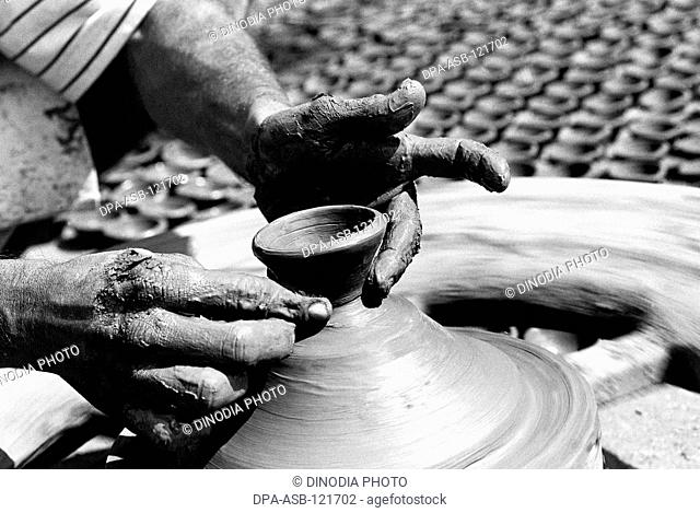 A potter sits on his potter's wheel as he makes diyas made out of clay for the Diwali festival in Kumbhaewada ; Dharavi ; Bombay now Mumbai ; Maharashtra ;...