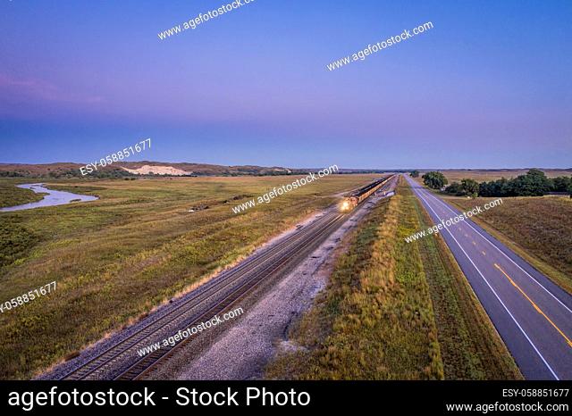 coal freight trains are running at dawn across Nebraska Sandhills along the Middle Loup River, aerial view