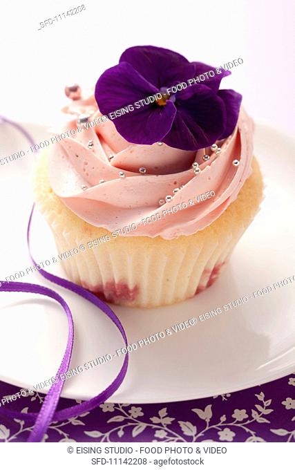 A cupcake decorated with a pansy