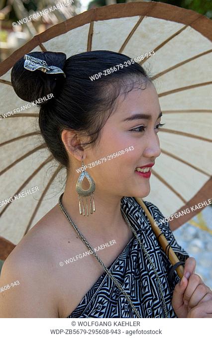 A portrait of a high school girl in traditional dress with a parasol in the UNESCO world heritage town of Luang Prabang in Central Laos
