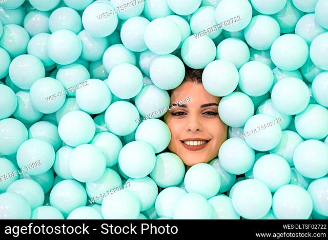Smiling woman amidst blue balls