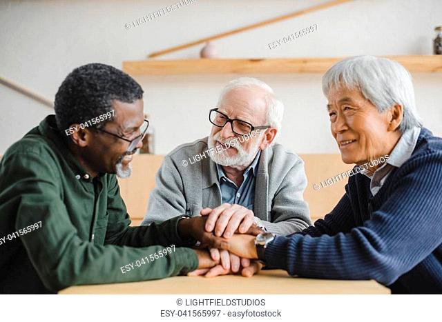 group of multiethnic senior friends making team gesture and smiling