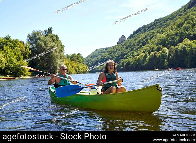 Girl with father canoeing in lake during vacation