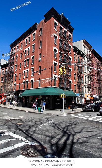 Red brick building, with corner store, against blue sky in New York city