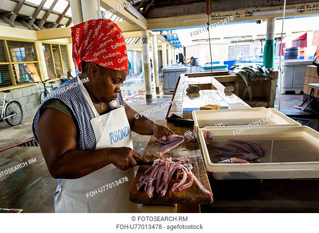 Woman filleting flying fish in Bridgetown fish market in Barbados - editorial use only