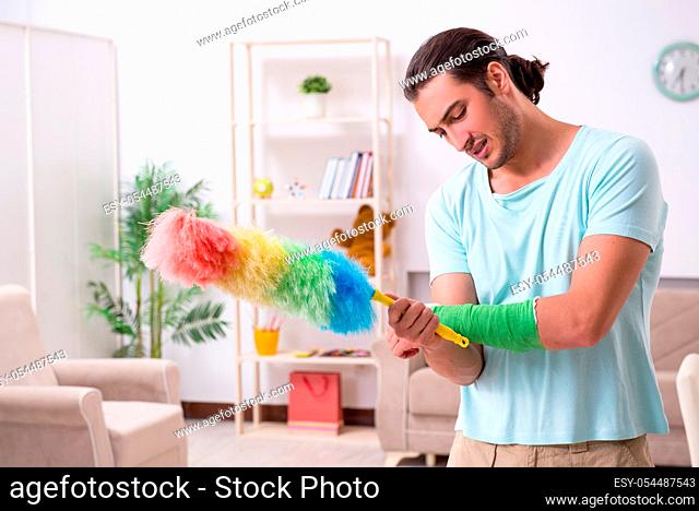 The young injured man cleaning the house