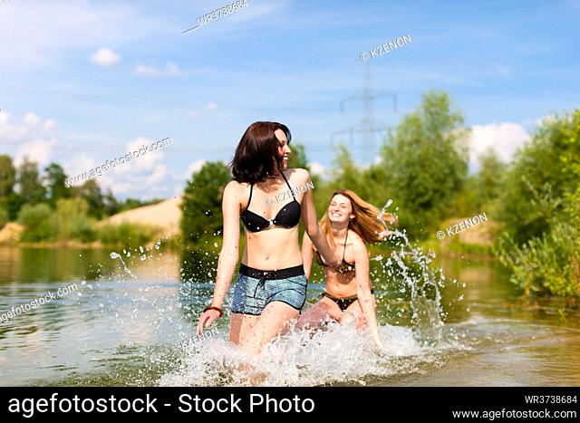 Two happy women having fun in summer at lake, they wearing swimwear