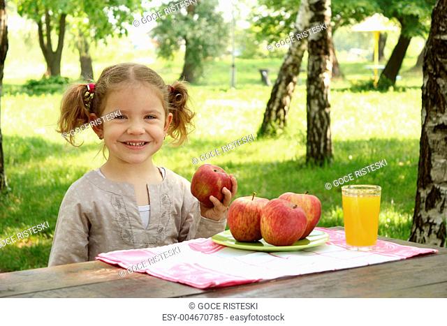 little girl with apple and juice in park