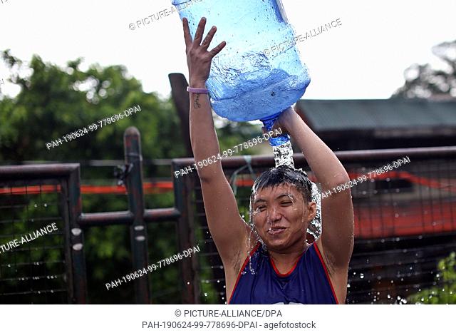 24 June 2019, Philippines, San Juan: A boy pours water on himself. Thousands of people take part in the 16th Wattah Wattah Festival