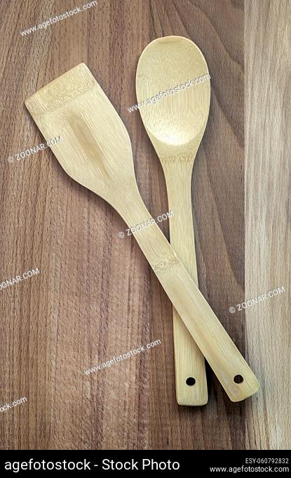 On a wooden table, kitchen utensils: a wooden spatula and a spoon. The view from the top, flat position, copy space