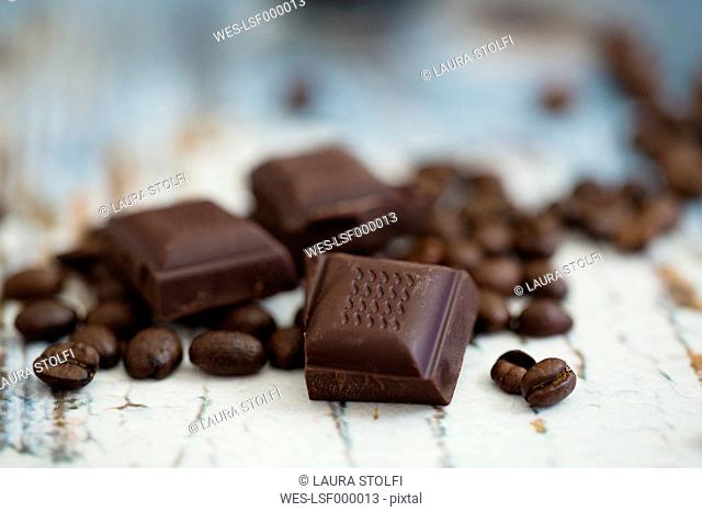 Roasted coffee beans and pieces of dark chocolate on wood