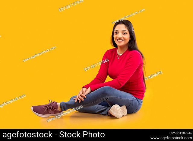 Happy young woman looking at camera with smile while sitting