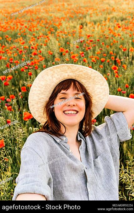 Beautiful happy woman wearing hat at poppy field