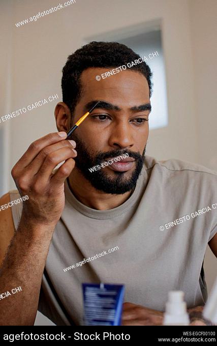 Man using eyebrow pencil at home