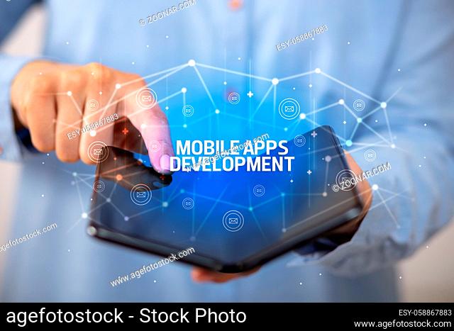 Businessman holding a foldable smartphone with MOBILE APPS DEVELOPMENT inscription, new technology concept