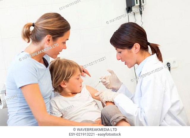 Child receiving an injection by a doctor in examination room