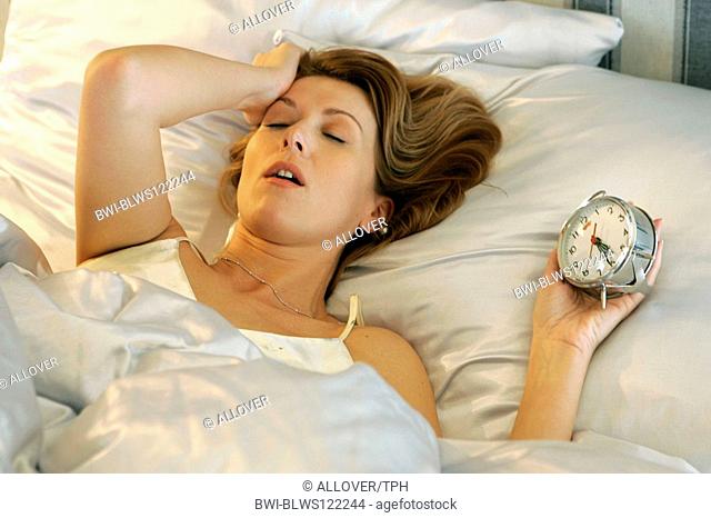 woman awaking by alarm clock in the morning