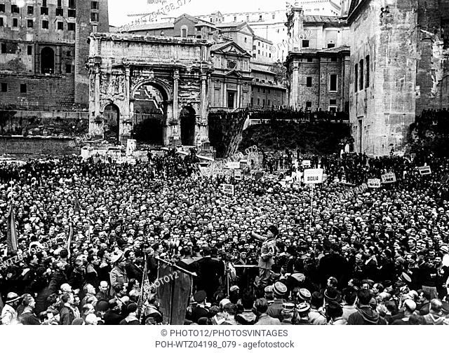 Benito Mussolini delivering a speech to Italians volunteering for war service, who have gathered at the Roman Forum, in front of the Septimus-Severus arch of...
