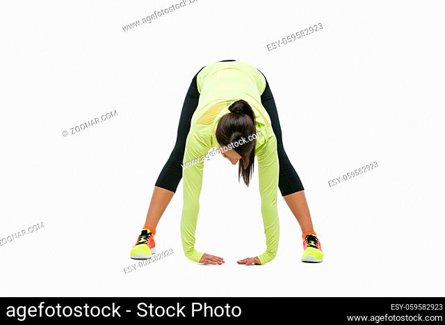 Young beautiful fit woman stretching legs. Isolated over white background. Copy space