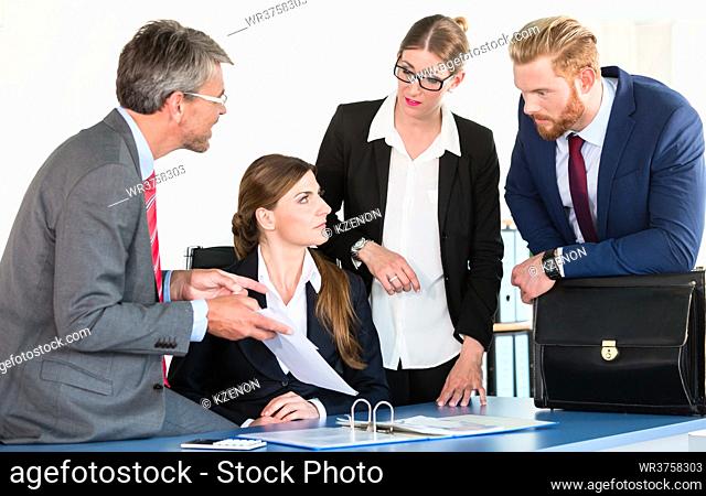 Team gathers around a desk, discussing a document