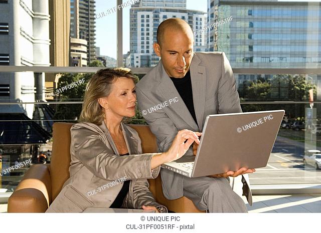 Businessman and woman looking at laptop