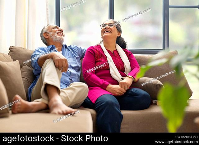 A SENIOR COUPLE SITTING TOGETHER AND LAUGHING HAPPILY