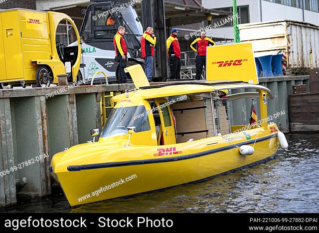 06 October 2022, Berlin: A Deutsche Post DHL solar ship is unloaded by employees at Westhafen Berlin. DHL launches parcel transport by water with an...