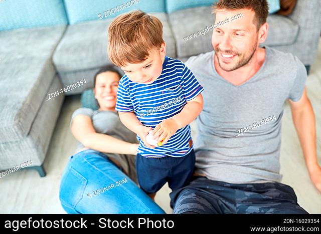 Junge spielt mit einem Spielzeug Flugzeug zusammen mit Eltern im Wohnzimmer